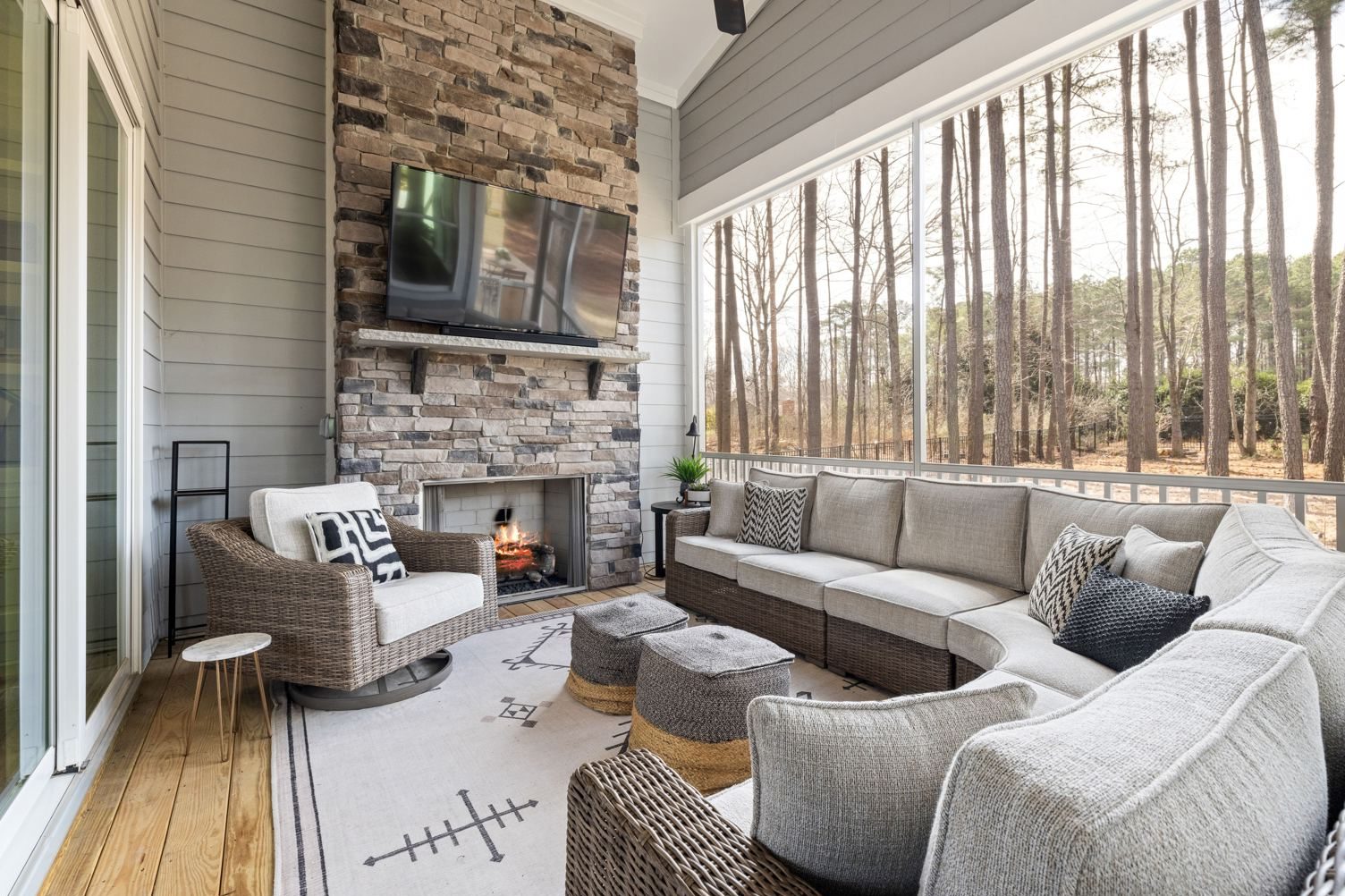 Screened porch with a stone fireplace, a mounted TV, and cushioned seating