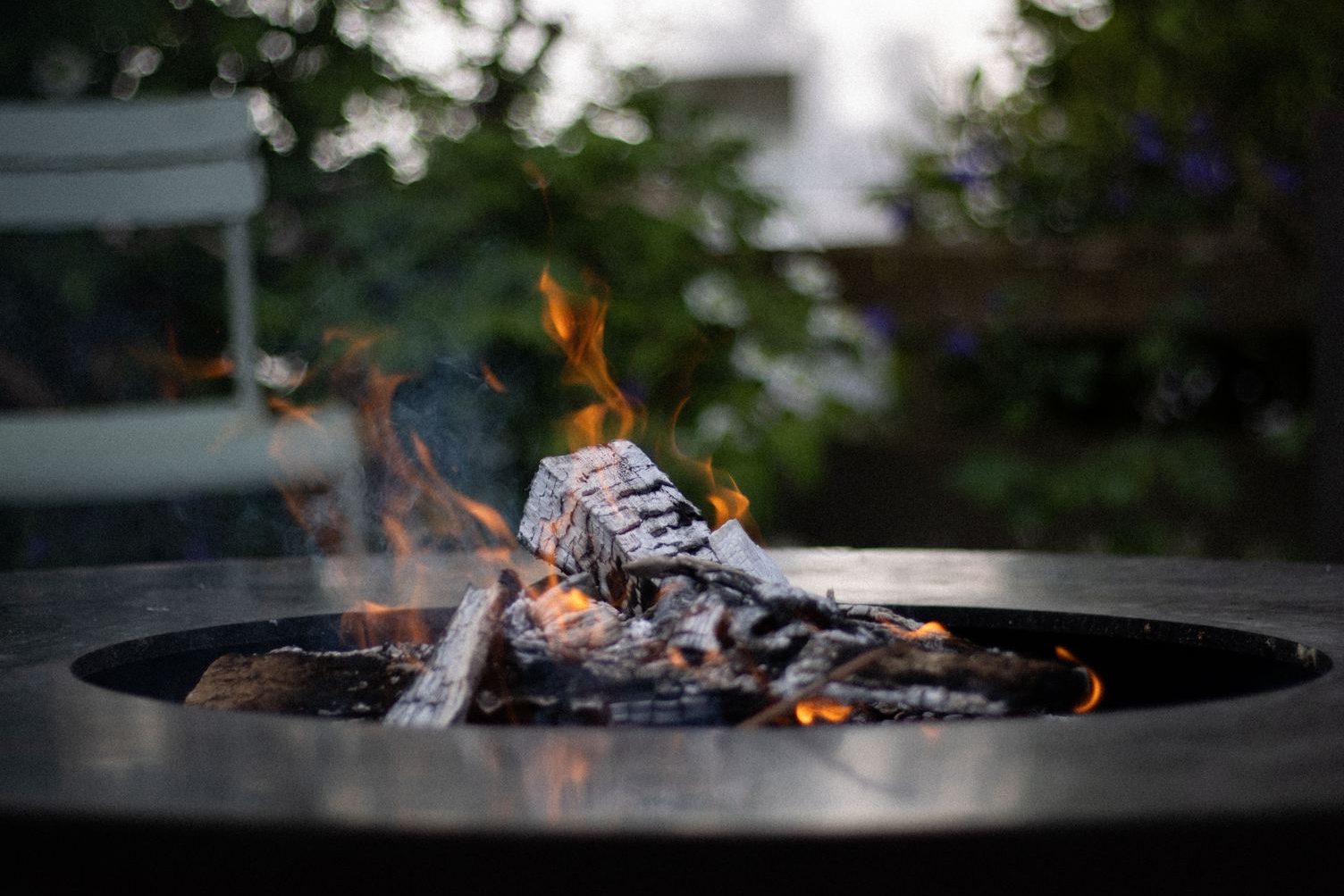 Logs burning in a fire pit on a backyard patio, shown up close