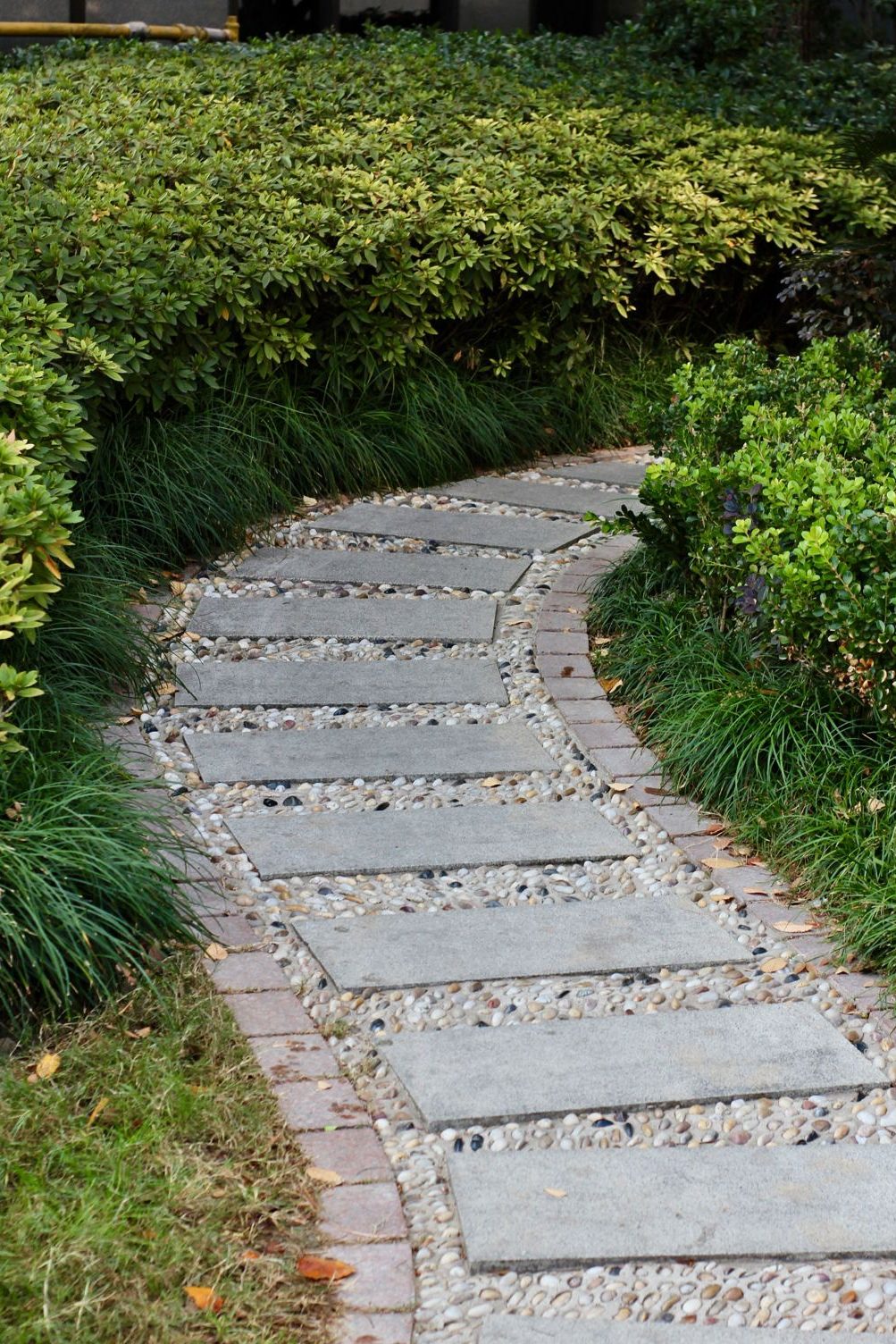 Concrete stepping stones set in loose pebbles, forming a path through a garden