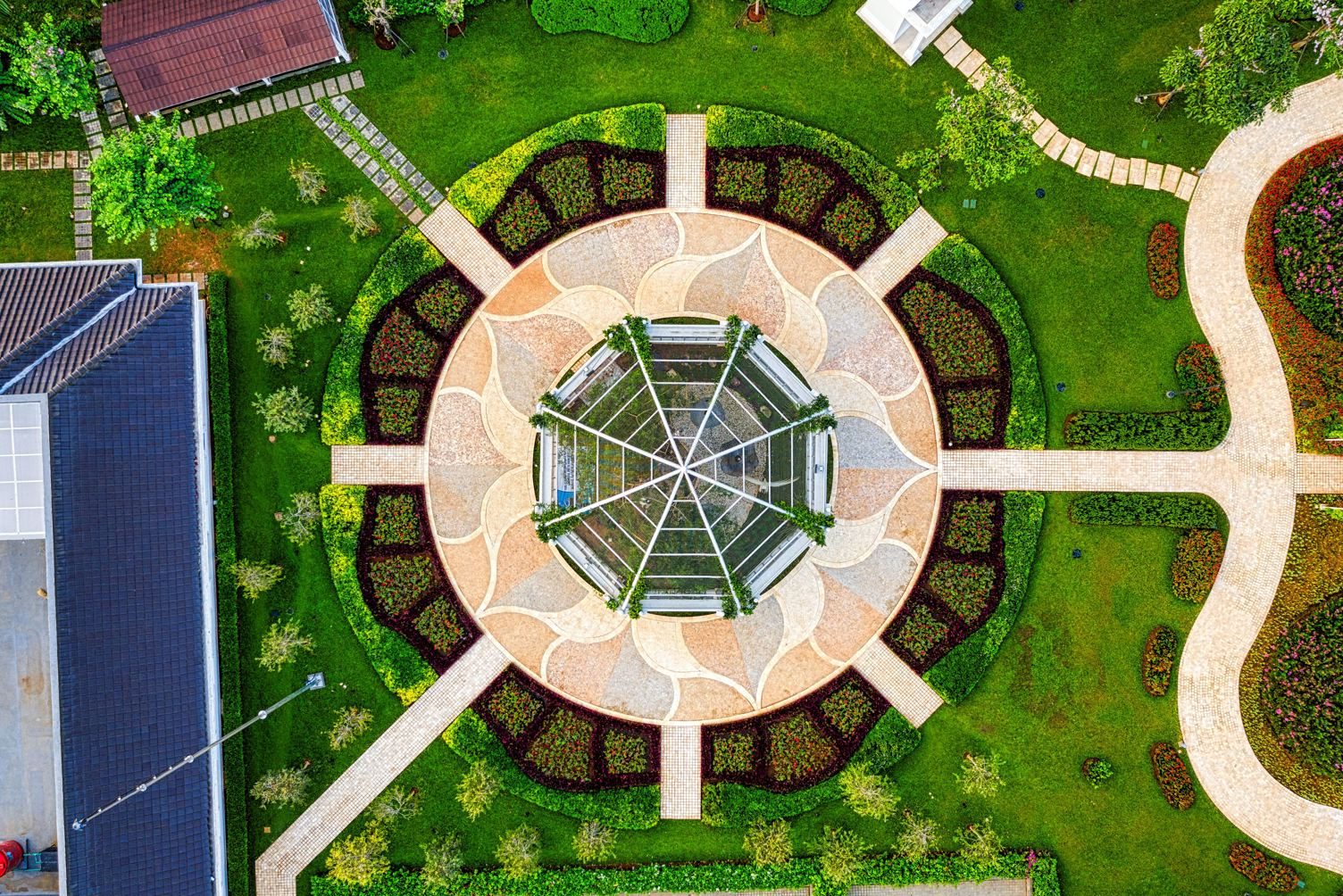 Overhead view of a round garden with a paver patio, clipped hedges, and a glass gazebo